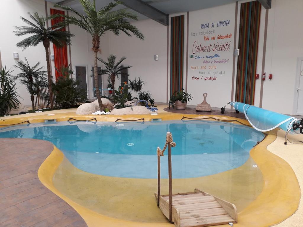 a large swimming pool in a room with palm trees at Résidence Beauvoir le Mont-Saint-Michel (9 gîtes de 2 à 5 personnes) in Beauvoir