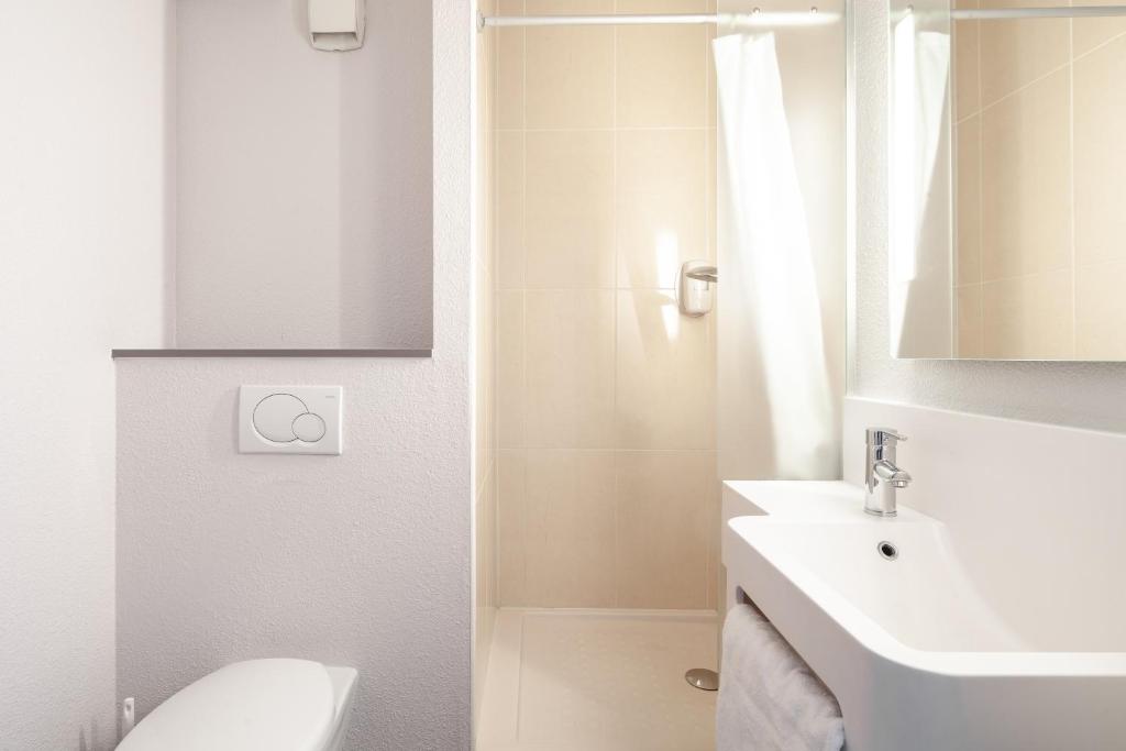 a white bathroom with a sink and a toilet at B&B HOTEL Paris Le Bourget in Le Bourget