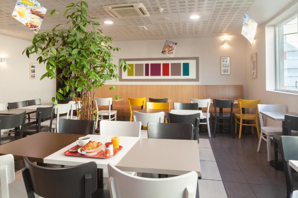 a dining room with white tables and chairs at B&B HOTEL Paris Le Bourget in Le Bourget