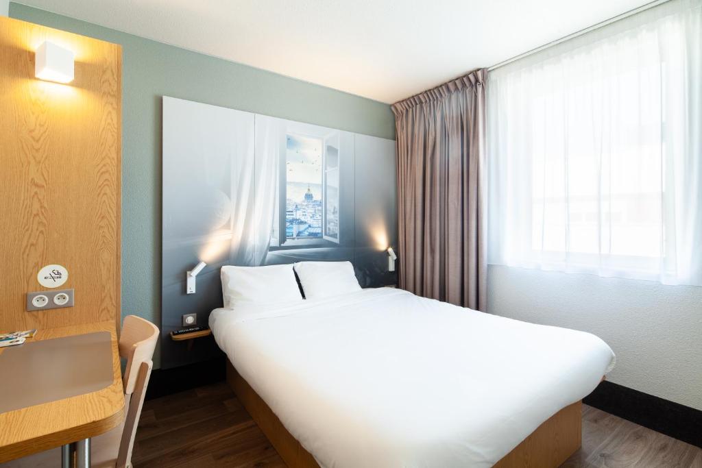 Un pat sau paturi într-o cameră la B&B HOTEL Paris Le Bourget