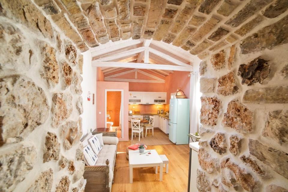 a living room with a stone wall and a table at Cozy eco cottage in Liapades