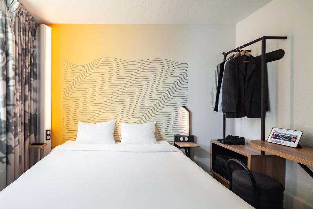 um quarto com uma cama branca e uma parede amarela em B&B HOTEL Paris Saint-Denis Pleyel em Saint-Denis