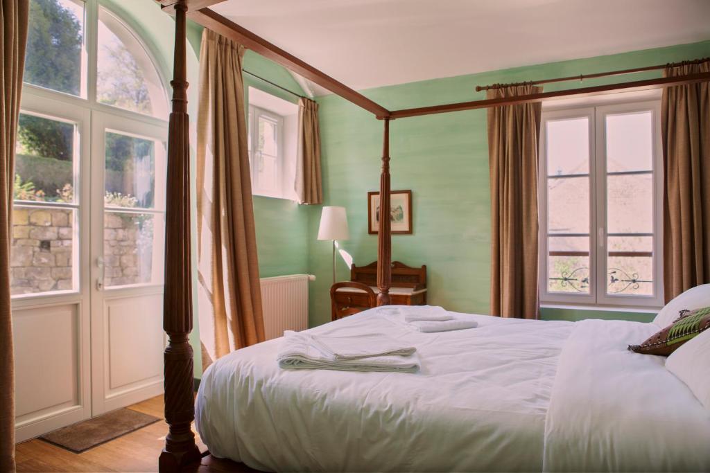 a bedroom with a bed and two windows at Chez Jules et Léonie in Valmondois