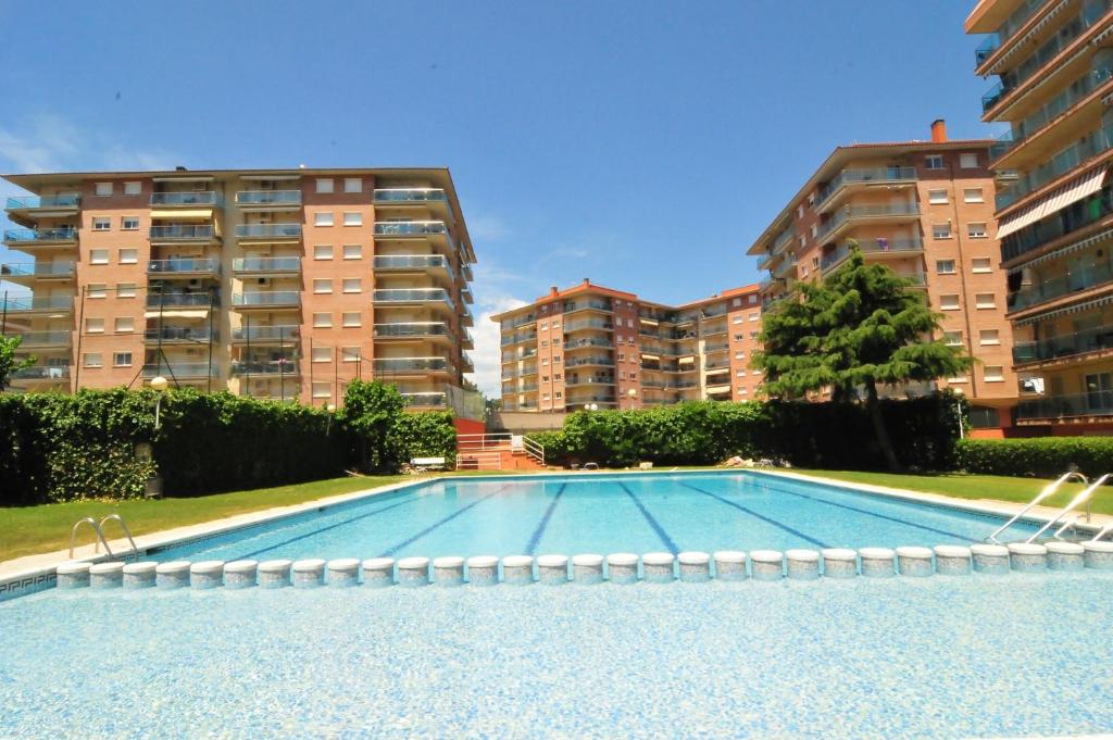 uma grande piscina com dois edifícios de apartamentos altos em HomeHolidaysRentals Aqua em Santa Susanna