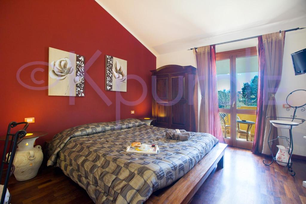 a bedroom with a bed with red walls and a window at LE API in Cagliari