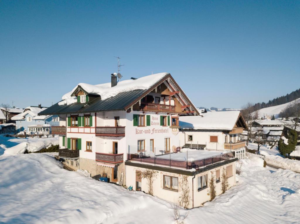 une maison dans la neige avec de la neige sur le toit dans l'établissement Haus Daheim, à Oberstaufen