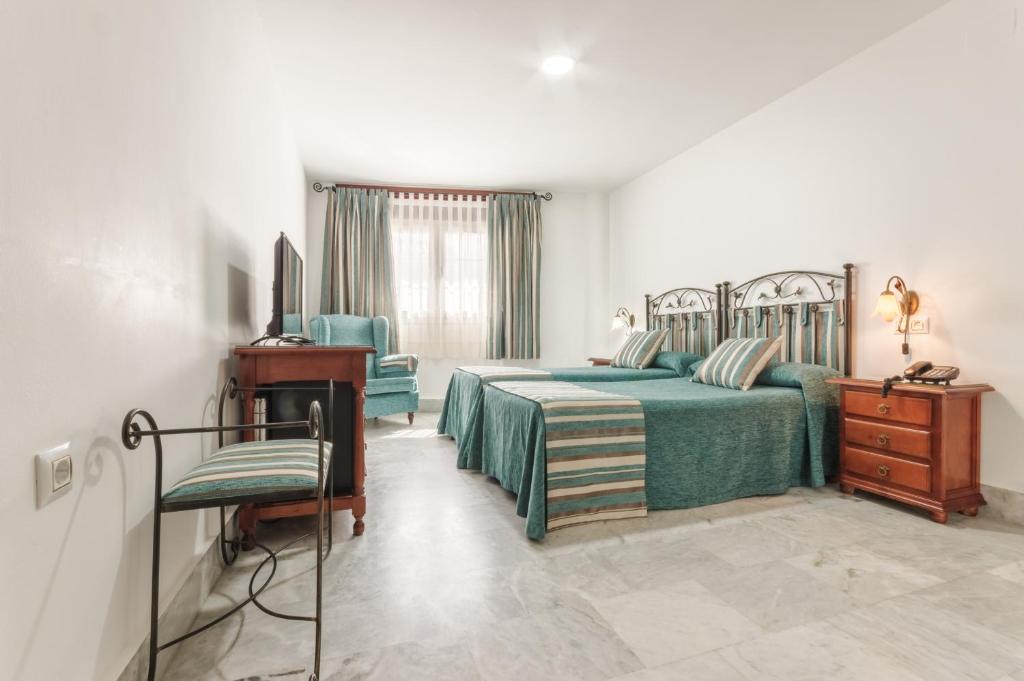 sypialnia z 2 łóżkami, biurkiem i telewizorem w obiekcie Hotel La Parrita w mieście Rota