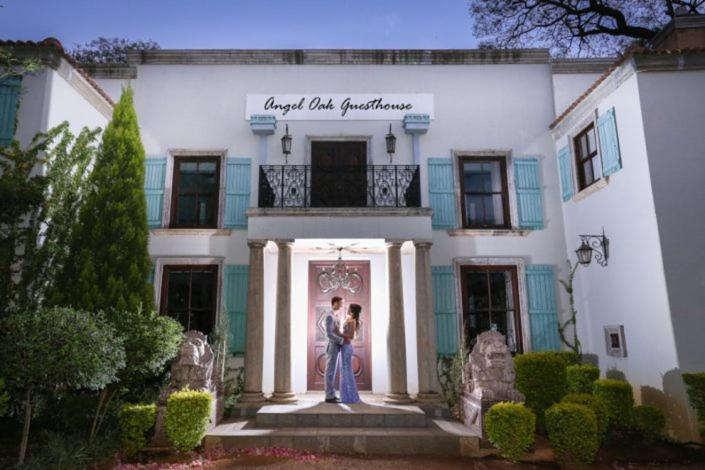 a couple standing in front of a white building at Angel Oak guesthouse in Brits