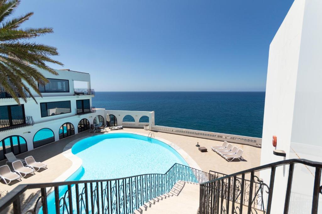 una piscina al lado de un edificio con el océano en Monte del Moro en San Agustin