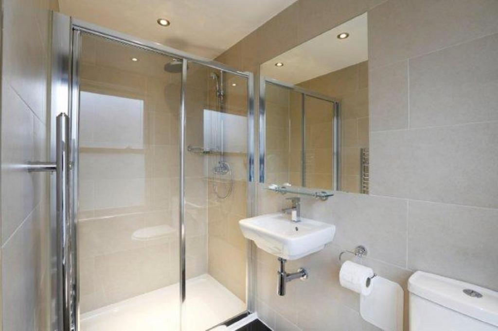 a bathroom with a sink, toilet and shower at Knaresborough Boutique Apartments in London
