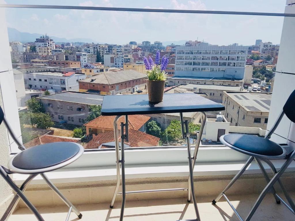 a table and chairs in front of a window at Rovena's Apartment - free parking in Tirana