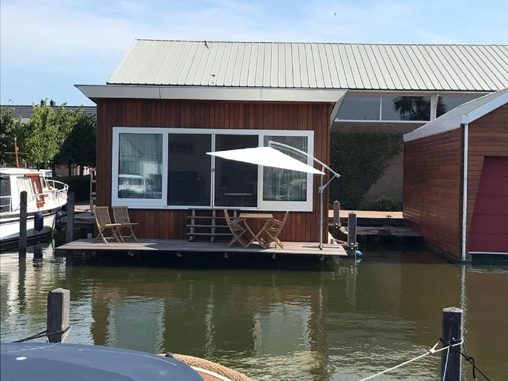 een huis met een paraplu op een dok in het water bij Nice houseboat with dishwasher, close to Amsterdam in Uitgeest