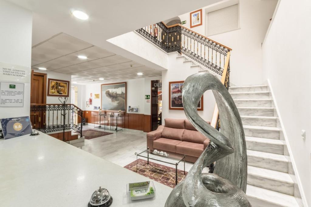 a living room with a staircase and a metal sculpture at Hotel La Parrita in Rota