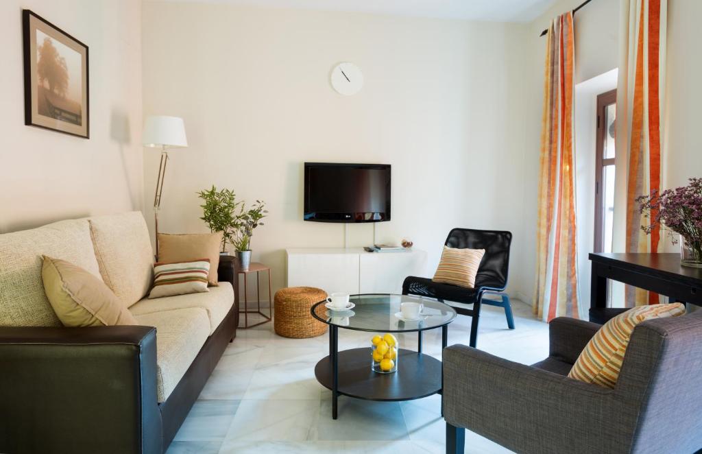 a living room with a couch and chairs and a table at Apartamentos Altamira in Seville