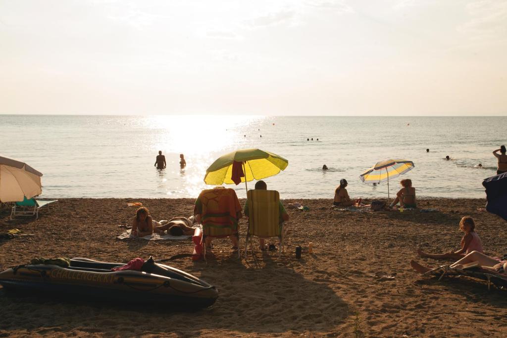 a group of people on a beach with umbrellas at Botanica Villas & Apartments in Neos Marmaras