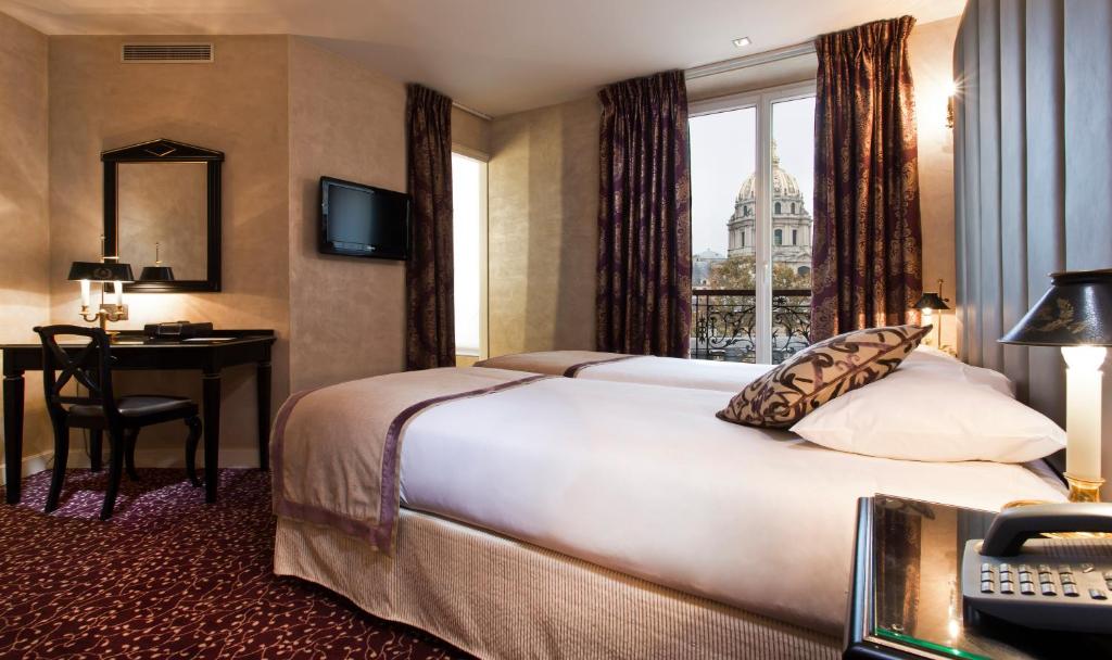 Cette chambre comprend un lit, un bureau et une fenêtre. dans l'établissement Hotel de L'Empereur by Malone, à Paris