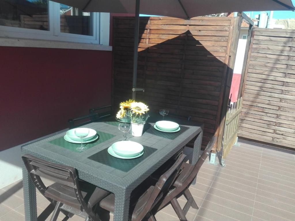 a table with four chairs and an umbrella on a patio at Lisbon Beach Apartments 1 in Costa da Caparica