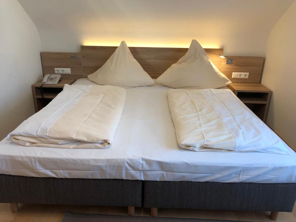 ein Bett mit weißer Bettwäsche und Kissen darauf in der Unterkunft Hotel Rose Heidelberg inklusive Frühstück & Saunanutzung in Heidelberg