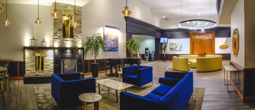 a lobby with blue chairs and a fireplace at Hotel Le Montagnais in Saguenay