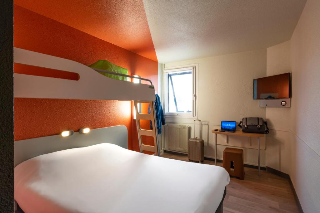 1 dormitorio con 1 cama con pared de color naranja en ibis Budget Vitry Sur Seine A86, en Vitry-sur-Seine