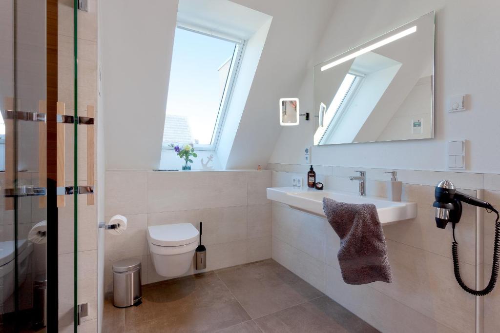 a bathroom with a sink and a toilet and a window at Düne 74 in Karlshagen