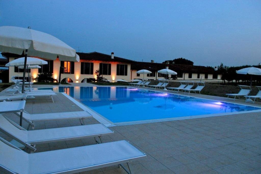 a large swimming pool with white chairs and umbrellas at Agriturismo Le Vai in Bardolino
