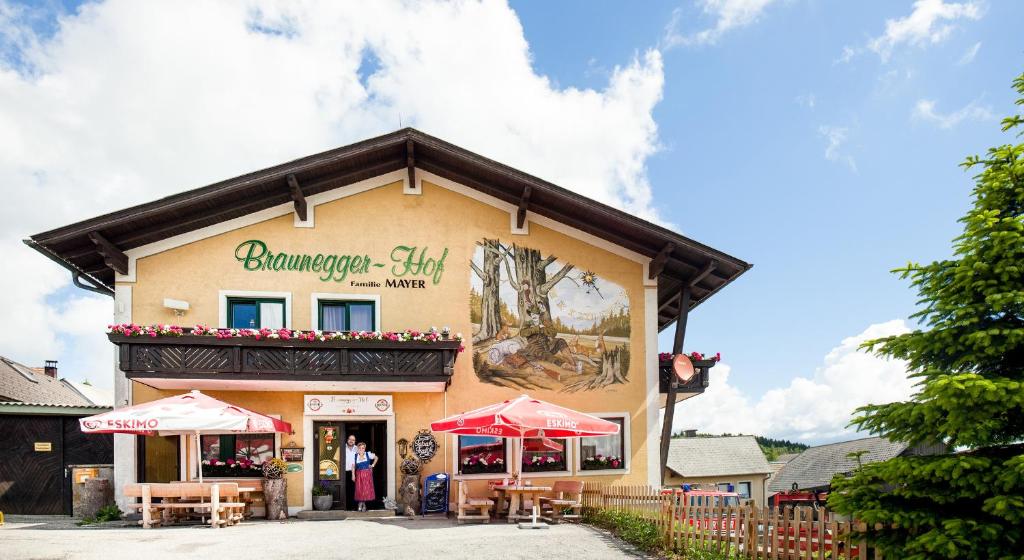 Braunegger-Hof Gasthof Mayer في Braunegg: مبنى امامه طاولات ومظلات