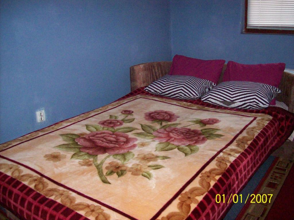 a bed with a floral blanket on top of it at Pansion Stari Konak in Sarajevo