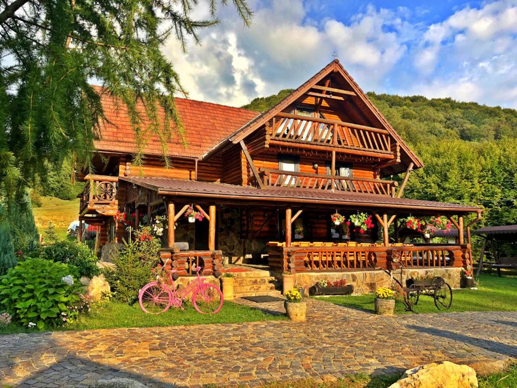 uma grande cabana com uma bicicleta cor-de-rosa à frente. em Cabana din Groapa Frumoasa em Rasnov