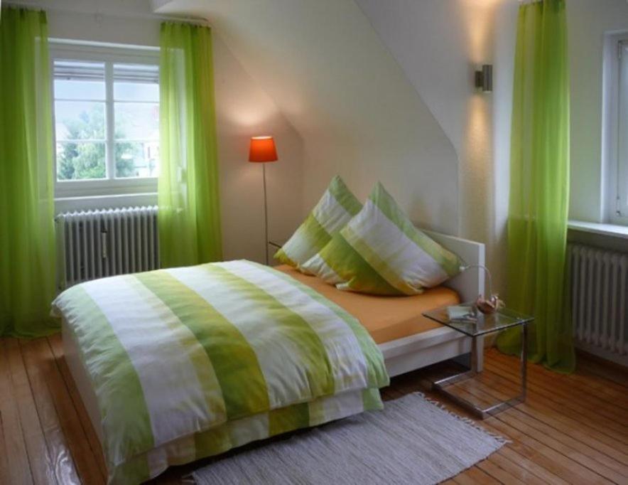 Schlafzimmer mit einem Bett mit grünen Vorhängen und einem Tisch in der Unterkunft NetteMaisonette in Saarbrücken