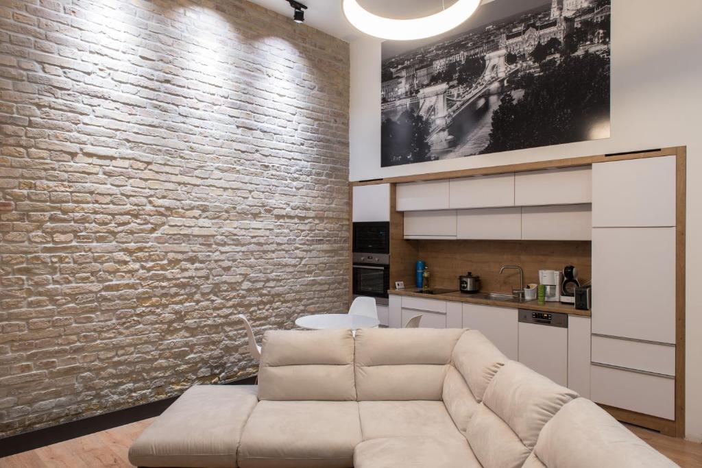 a living room with a couch and a brick wall at New Loft Style Appartman in the heart of the City in Budapest