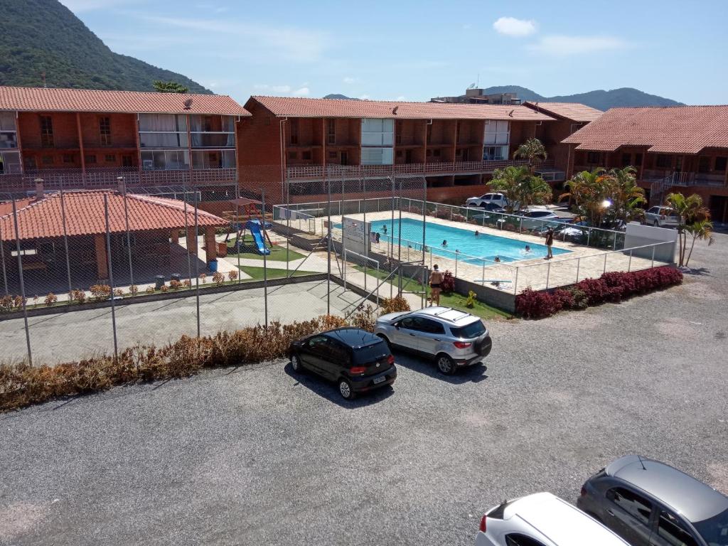 two cars parked in a parking lot next to a swimming pool at Maranduba Ville II in Ubatuba