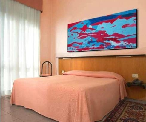 una camera con letto rosa e un dipinto sul muro di Giardino Hotel a Milano