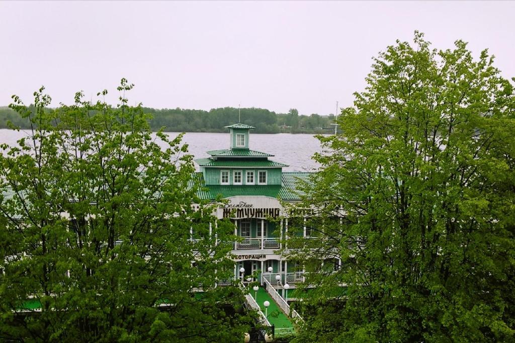 un grand bâtiment vert avec une tour au milieu des arbres dans l'établissement Aqua Hotel Volzhskaya Zemchuzhina, à Yaroslavl