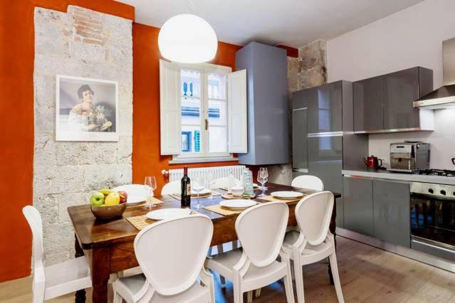 een keuken met een houten tafel en witte stoelen bij New Galileo in Pisa