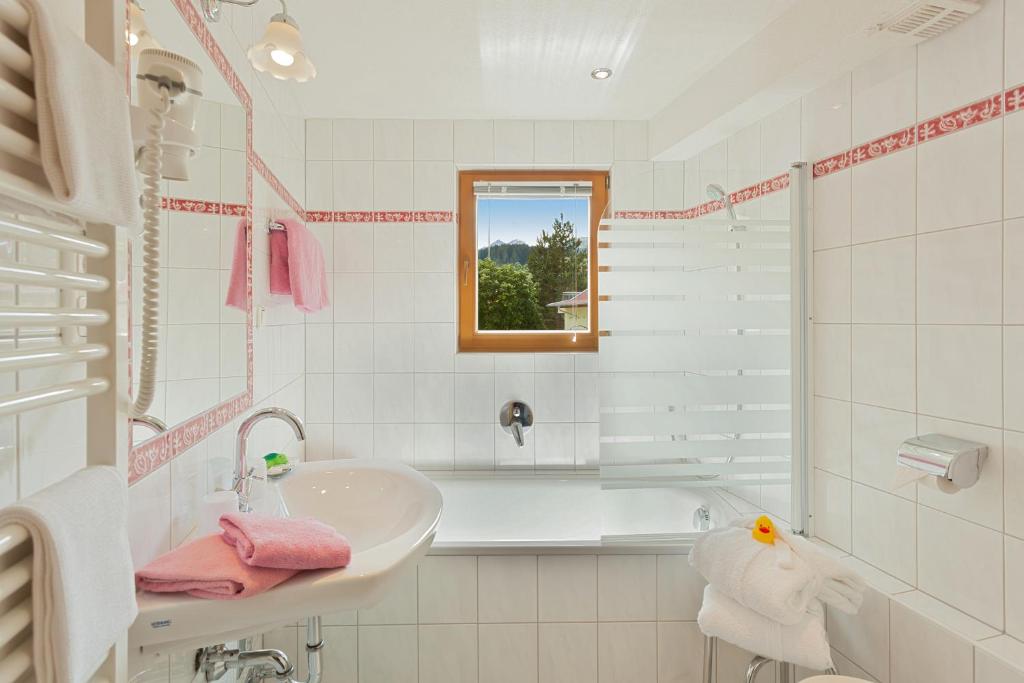 a white bathroom with a sink and a tub at Hotel Montfort in Sankt Anton am Arlberg
