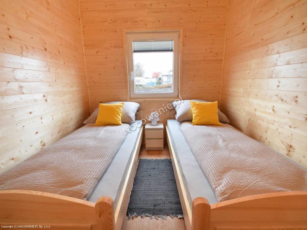 two beds in a small room with a window at MożeMorze? Ośrodek Domków Letniskowych in Chłopy