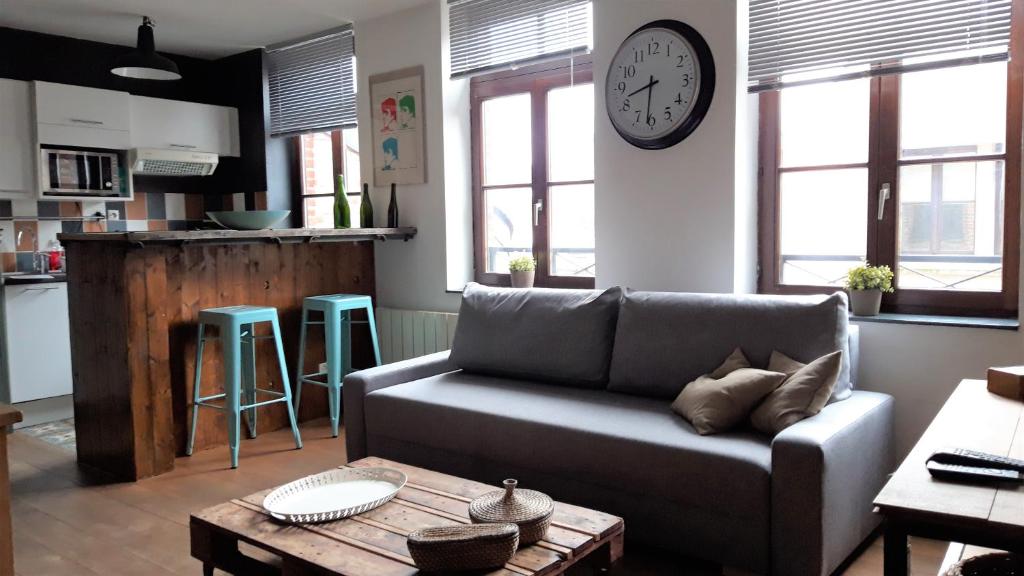un salon avec un canapé et une horloge au mur dans l'établissement Little Suite - Louise, à Lille