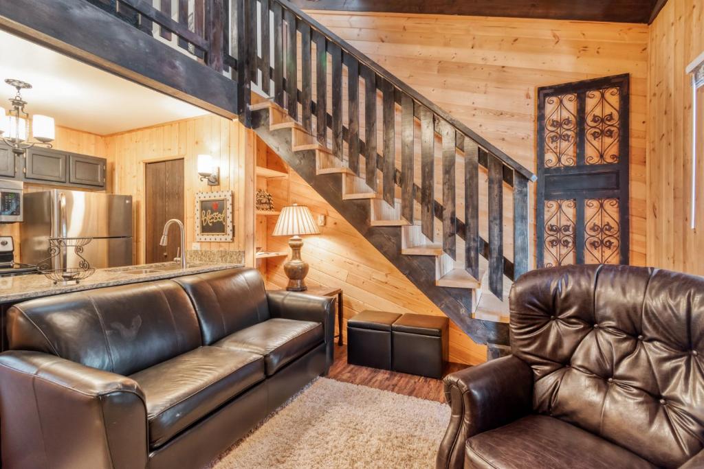 a living room with leather furniture and a staircase at Redwood Commons B12 in Angel Fire