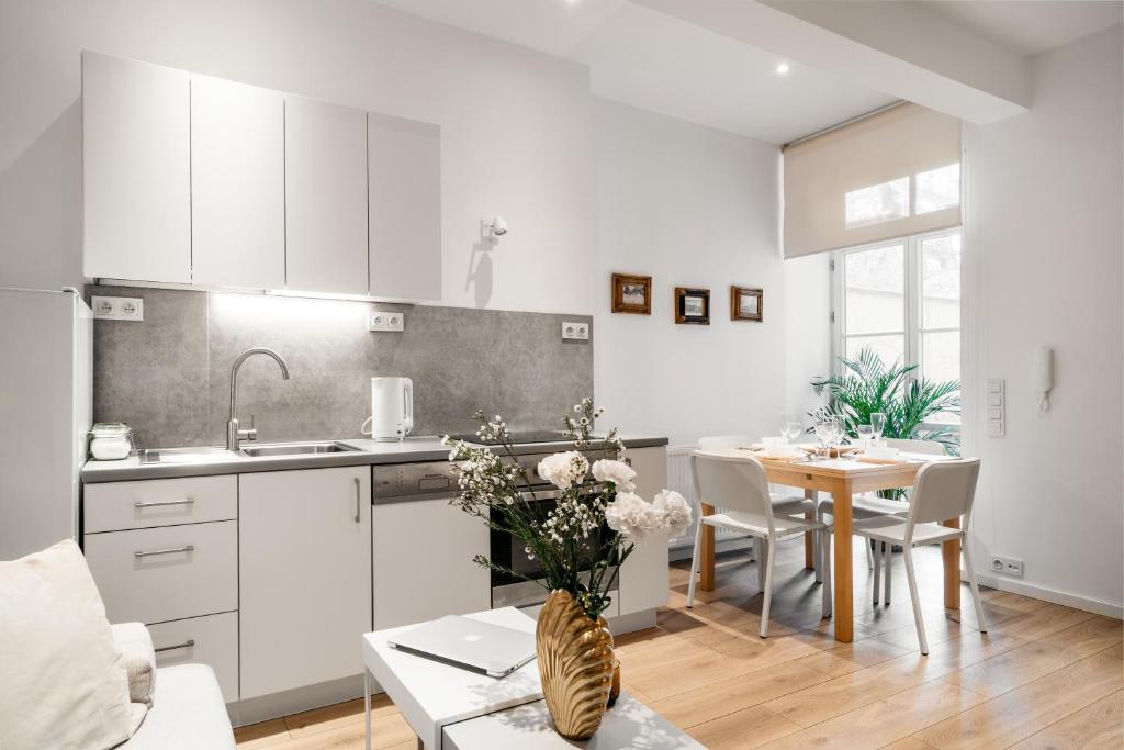 a kitchen and dining room with white cabinets and a table at Art Studios - LoftAffair in Kraków