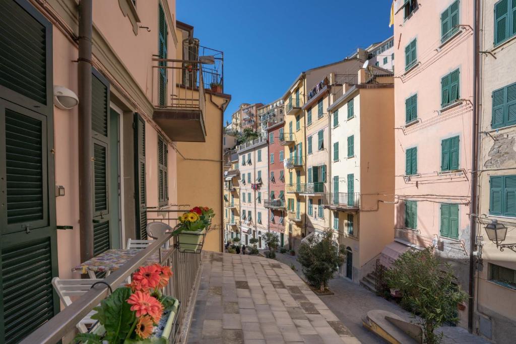 an alley in the city with flowers on a balcony at Da Elisa in Riomaggiore