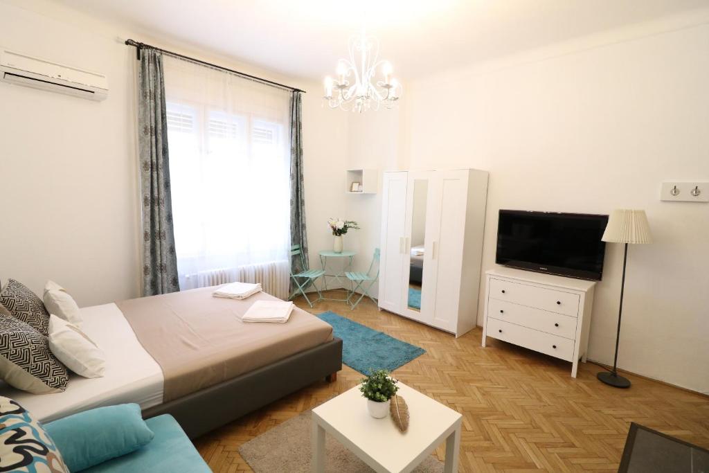ブダペストにあるReal Apartments Wesselényi IIIのベッドルーム(ベッド1台、テレビ、ソファ付)