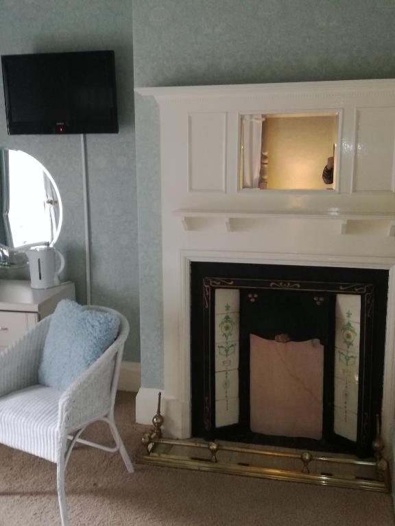 a living room with a fireplace with a chair and a mirror at Captains Lodge in Newbiggin-by-the-Sea
