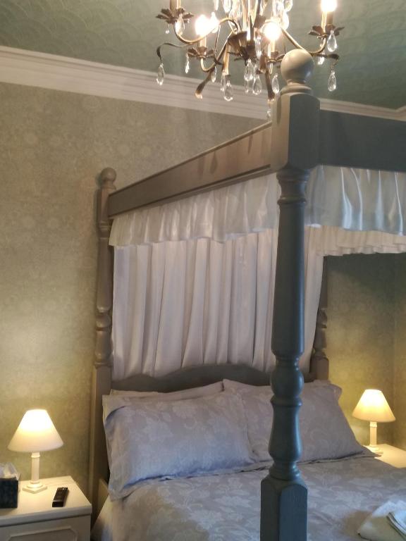 a bedroom with a canopy bed with a chandelier at Captains Lodge in Newbiggin-by-the-Sea