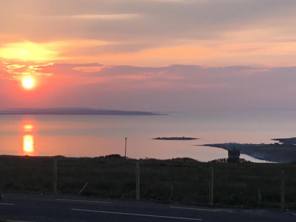 um pôr-do-sol sobre um corpo de água com o oceano em Zepher Apartment em Doolin