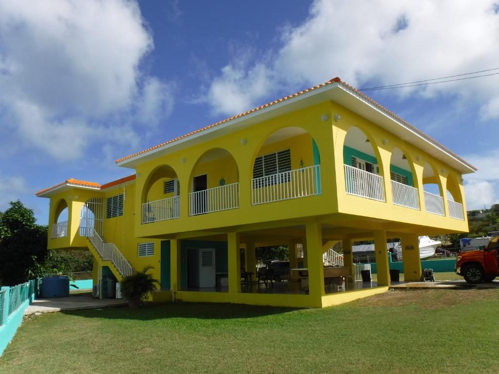 a yellow house with a green at La Casona Beach House in Fajardo