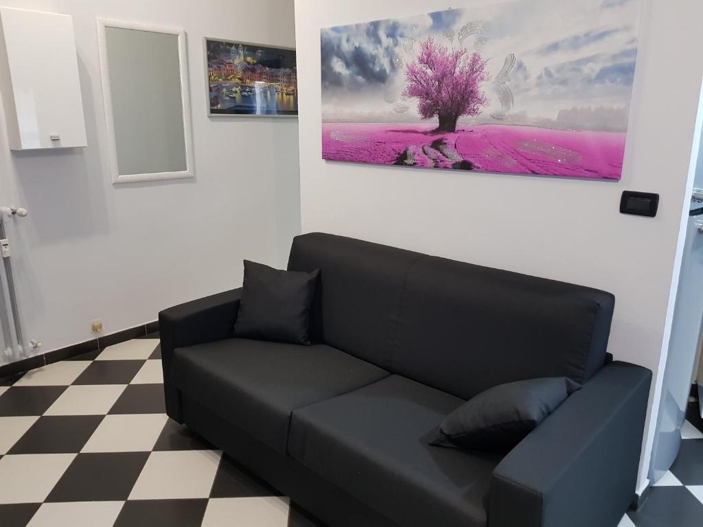 un sofá negro en una habitación con una pintura en la pared en Appartamento Saretta en Asti
