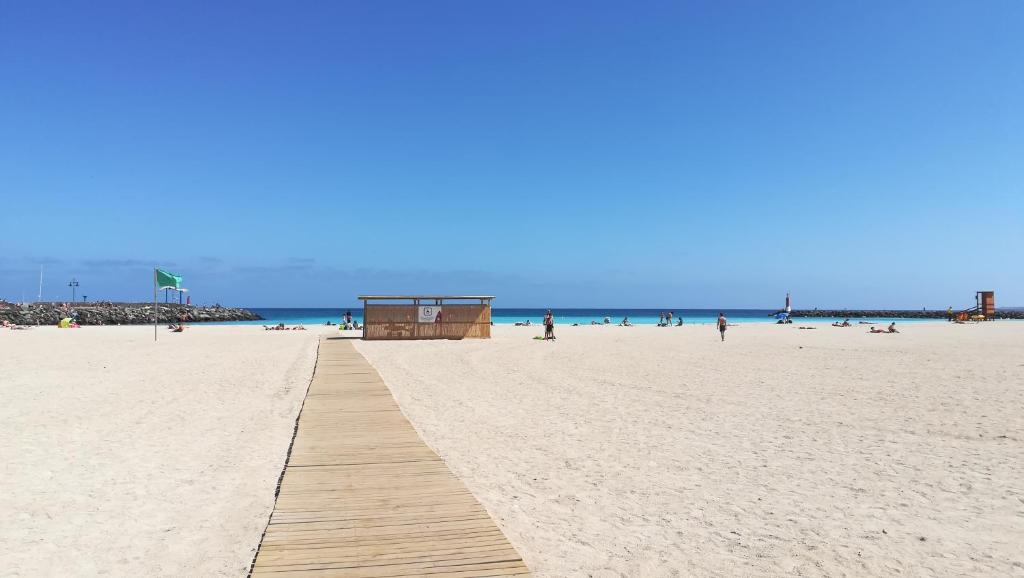 a sandy beach with a wooden pathway in the sand at Bed & Breakfast Descanso y Relax in Puerto del Rosario