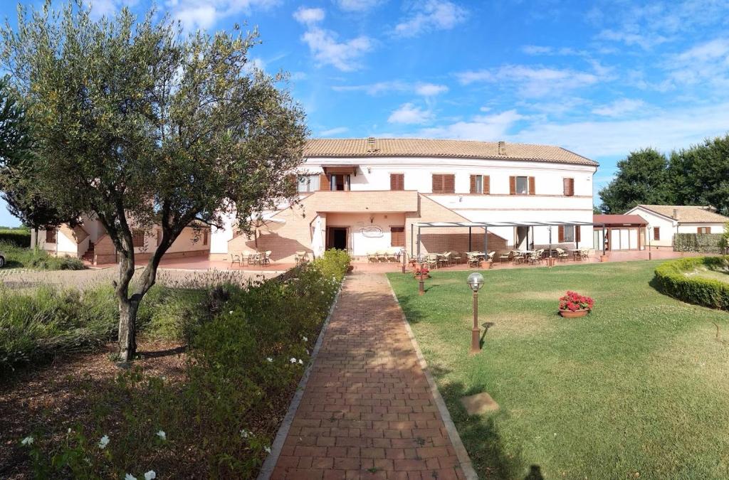 a large house with a brick walkway in front of a yard at Hotel Ristorante Mira Conero in Porto Recanati