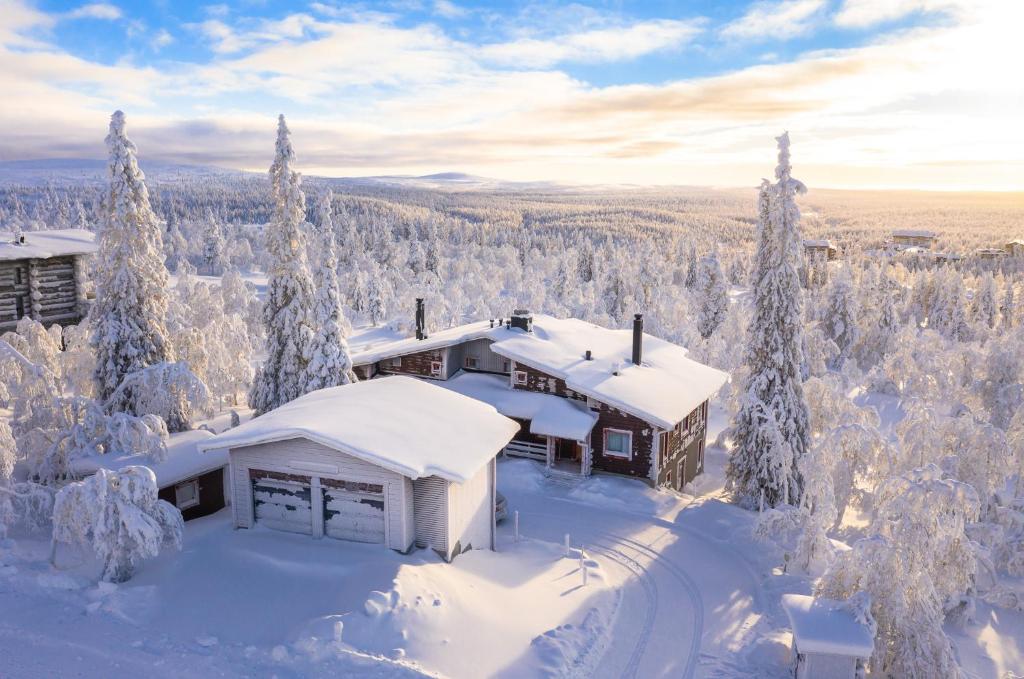 a house covered in snow in the woods at Kiisa A and B with aurora rooms in Saariselka